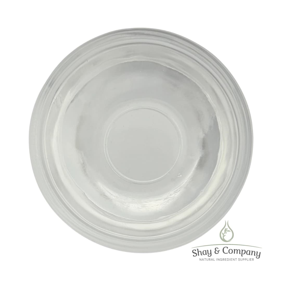 Clear glass bowl viewed from above containing transparent liquid, Shay & Company natural ingredient supplier logo.