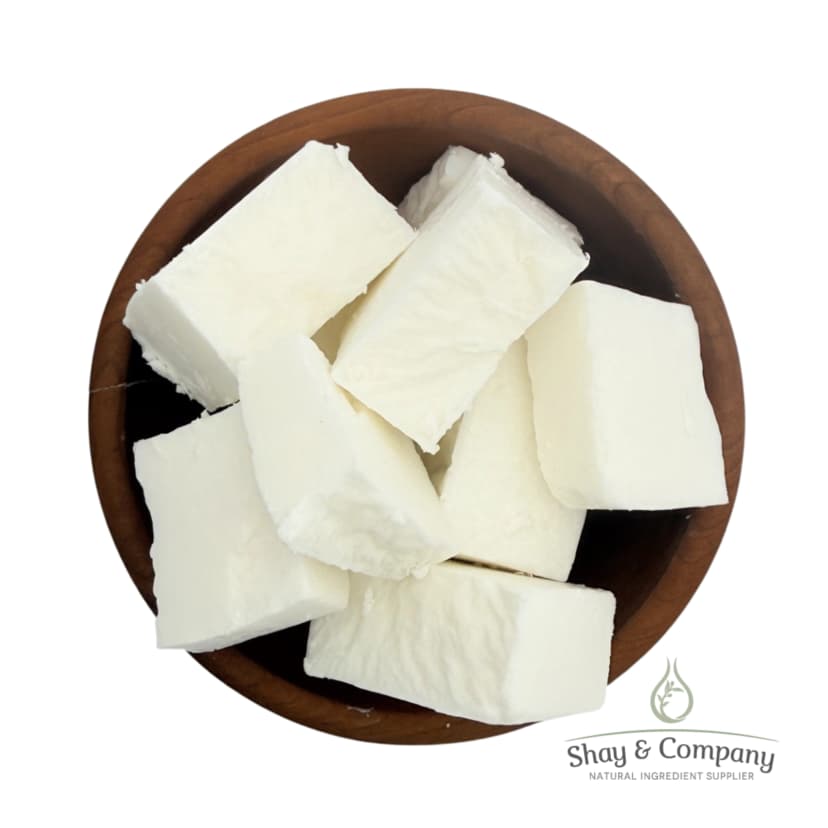 Creamy white shea butter chunks in a wooden bowl from Shay and Company.