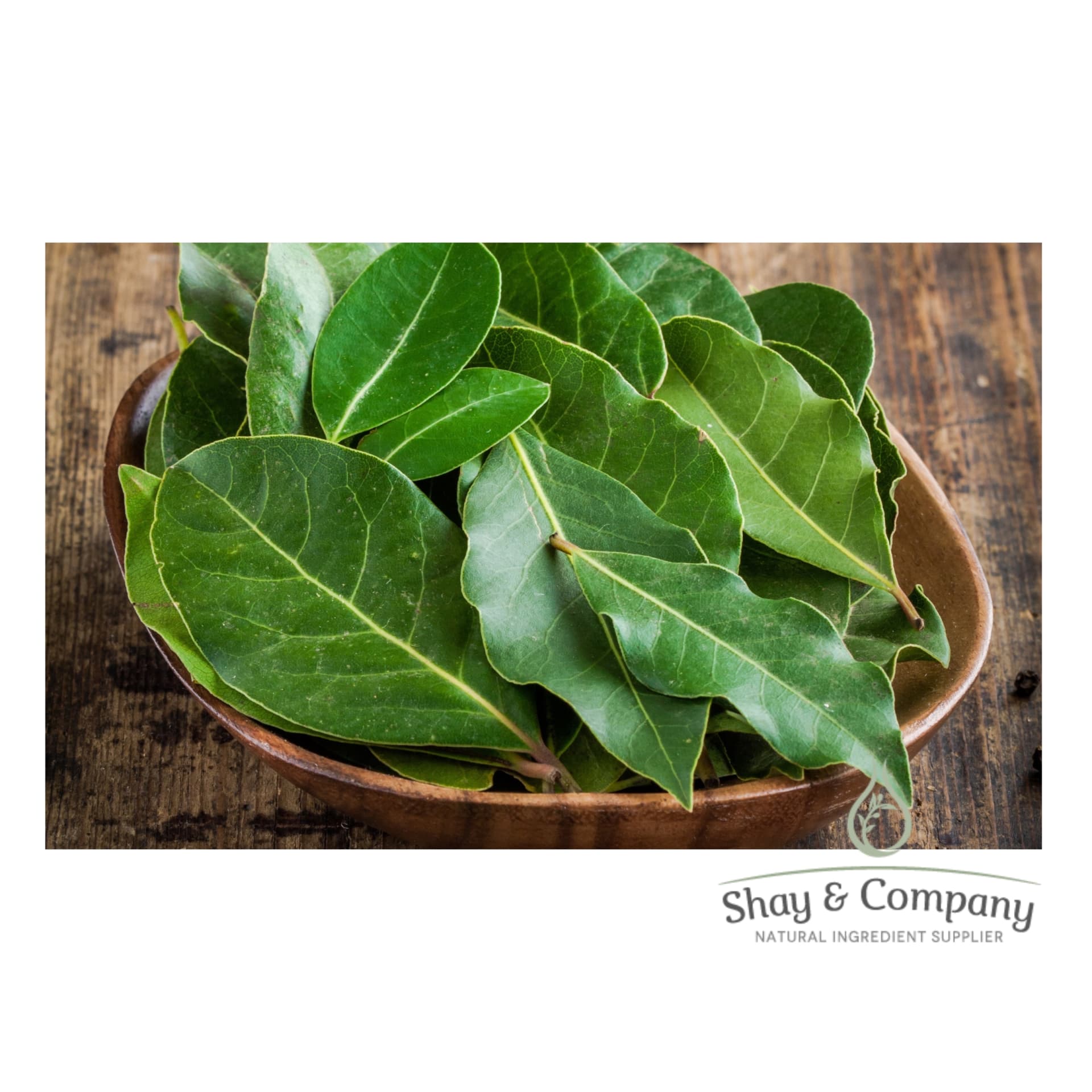 Wooden bowl filled with Clove leaves on a wooden table.