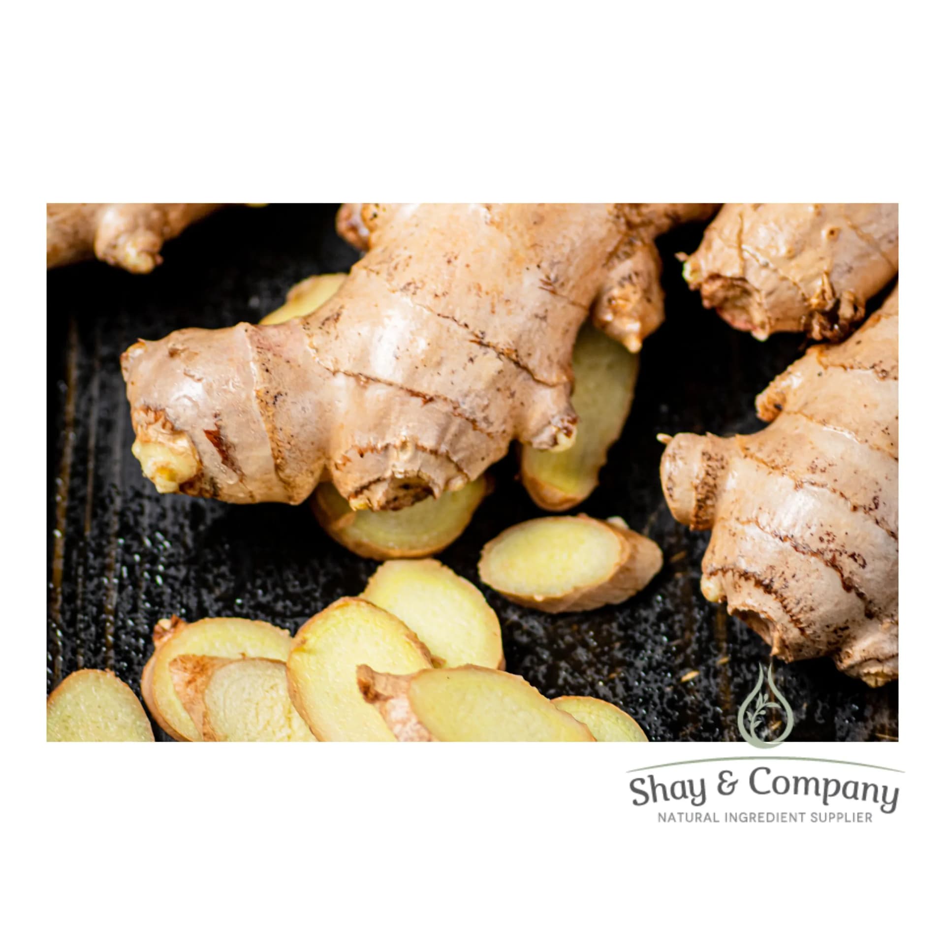Two ginger roots on a black background with slices of ginger root in the foreground.