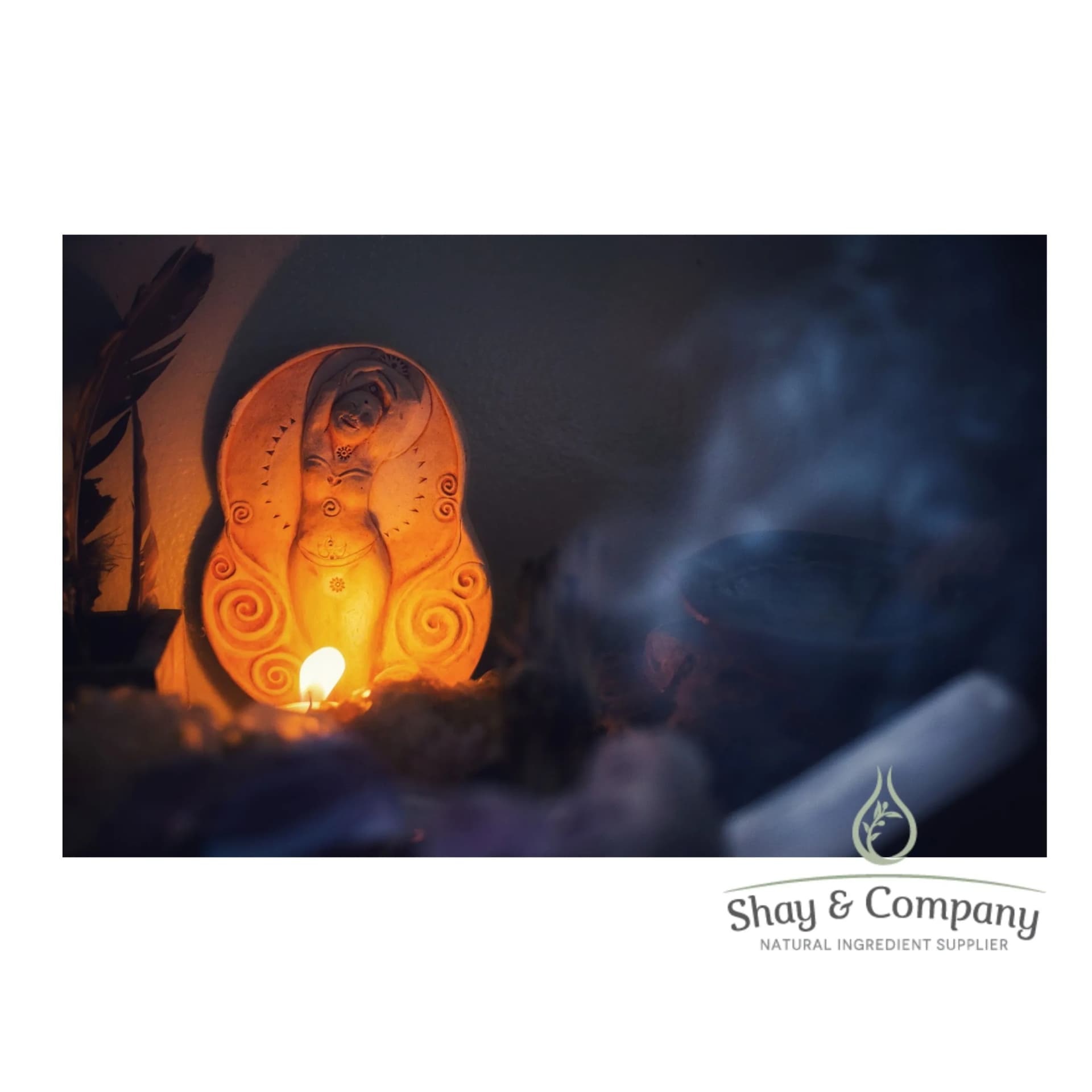 A candle illuminates a clay fertility goddess with smoke in the foreground.