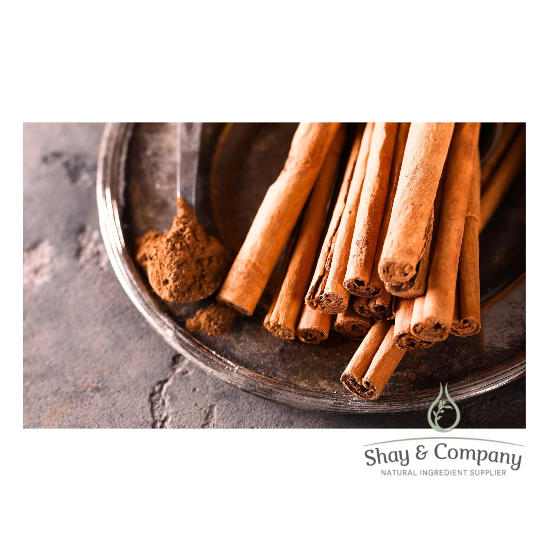 Silver bowl holds cinnamon sticks and a spoon full of ground cinnamon.